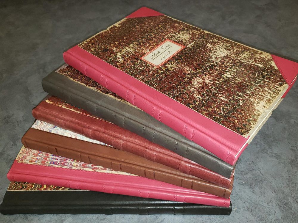 Stock books with marbled covers and leather bindings in various color fanned out.