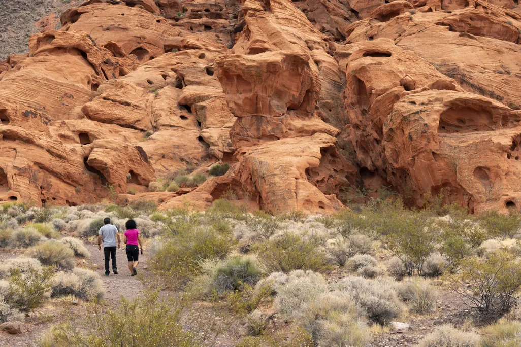 Two people hiking among red sandstone formations