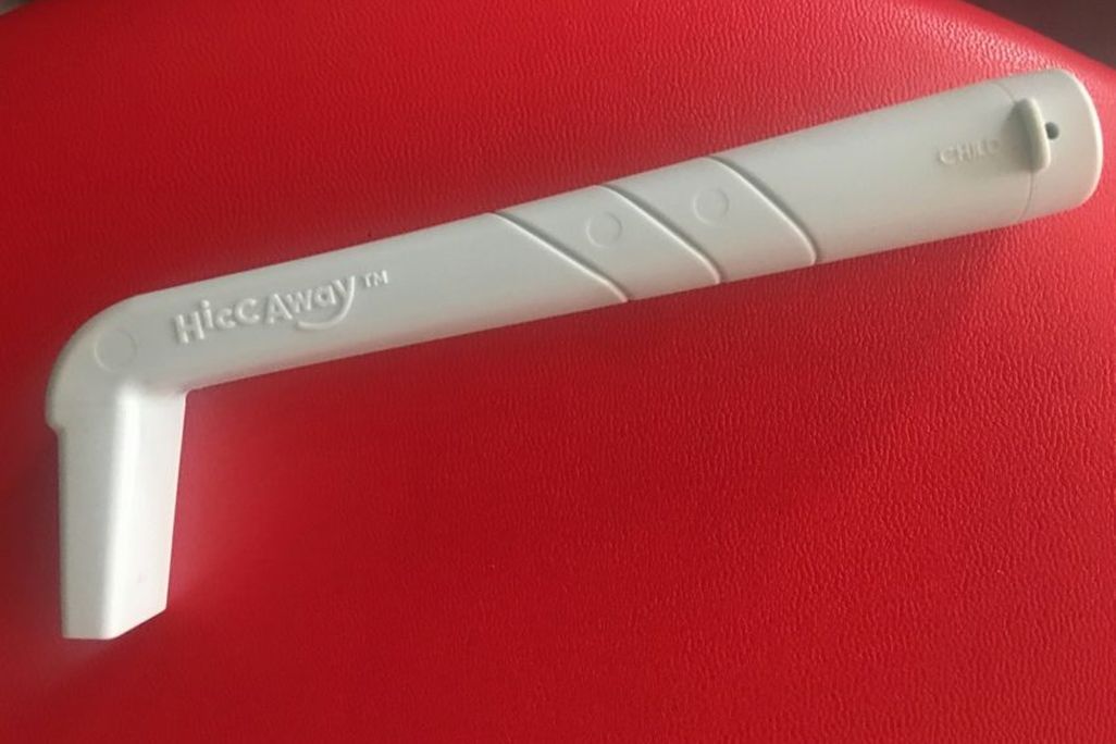 A blue L-shaped straw device sits on a red surface