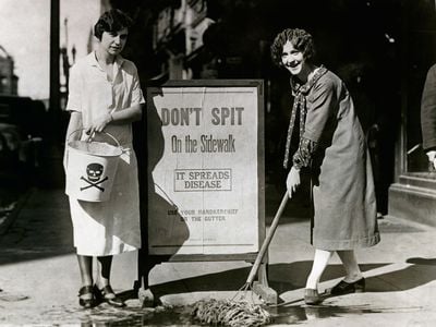 Allene Goodenough (right) and Helyn James of the Young Women's Christian Association mop up a spot on the sidewalk where someone expectorated by an anti-spitting sign during a public health campaign in Syracuse, New York, in 1900. 