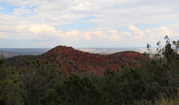 A beautiful rust colored hill against a blue, cloudy sky.