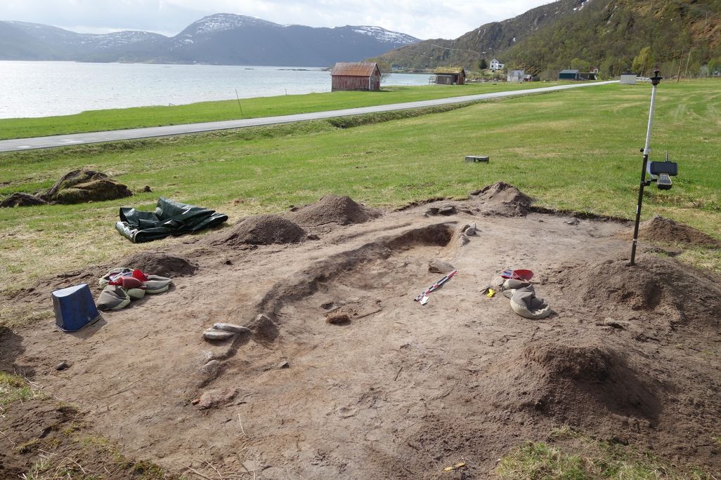 Archaeological dig site overlooking green grass and water