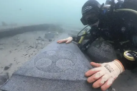 A marine archaeologist examines one of the engraved Purbeck gravestones recovered from the 13th-century Mortar Wreck.