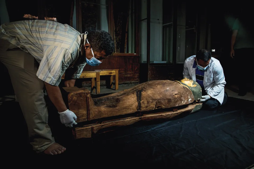 A coffin bearing the well-preserved mummy of a woman named Ta-net-Imen, dating to the Ptolemaic era more than 2,000 years ago. The gilded mask attests to her wealth and status.