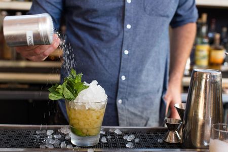 Bartender making mint julep cocktail.