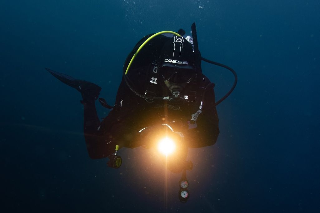 Scuba diver with a light pointing at the camera