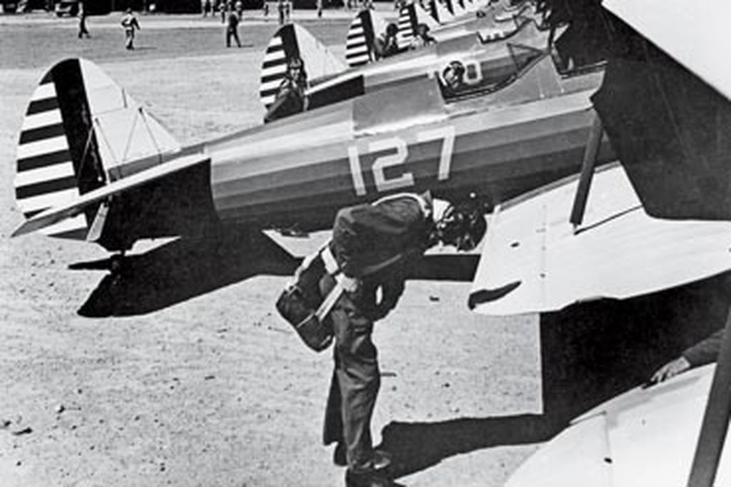 Man wearing a parachutes next to a plane during WWII.
