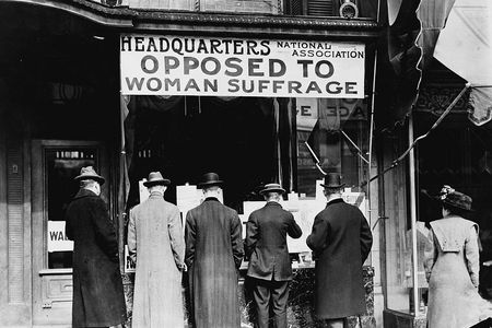 Men looking at material posted in the window of the National Anti-Suffrage Association headquarters, around 1911.
