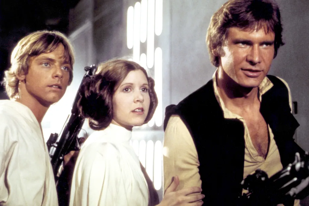 A man in a white tunic, a woman in a white dress and a man in a black vest