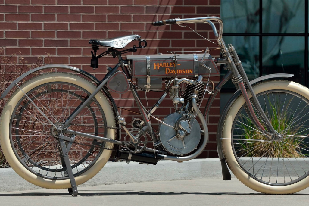 Gray vintage motorcycle in front of brick wall