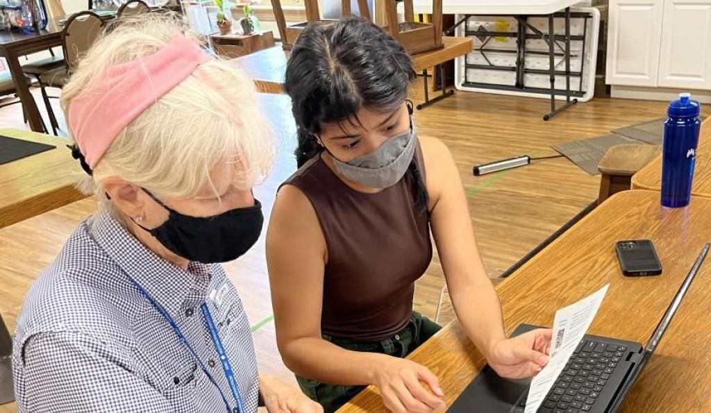 Two masked people look at a computer screen in a scientific lab.