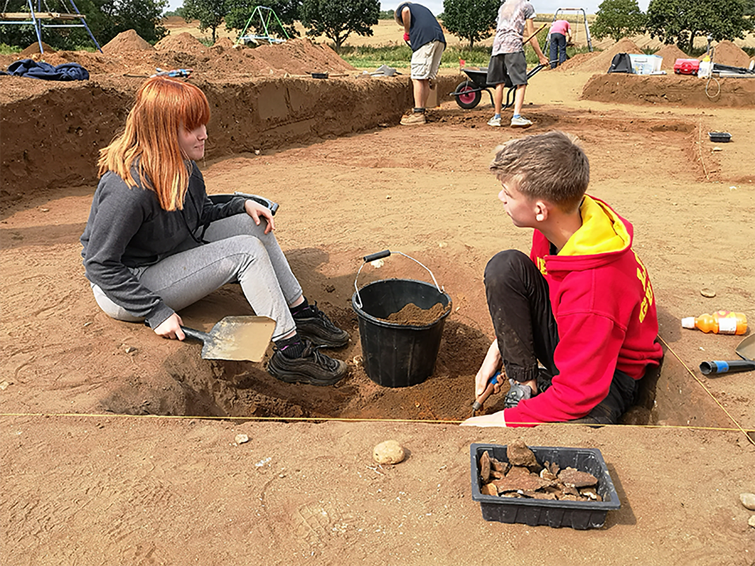 A young boy and woman sitting by hole with digging materials