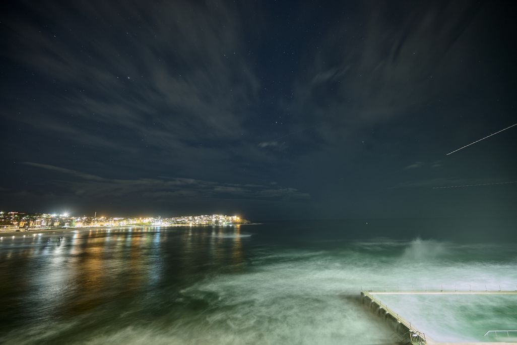 Meteor streaking across the sky with city lights in the background