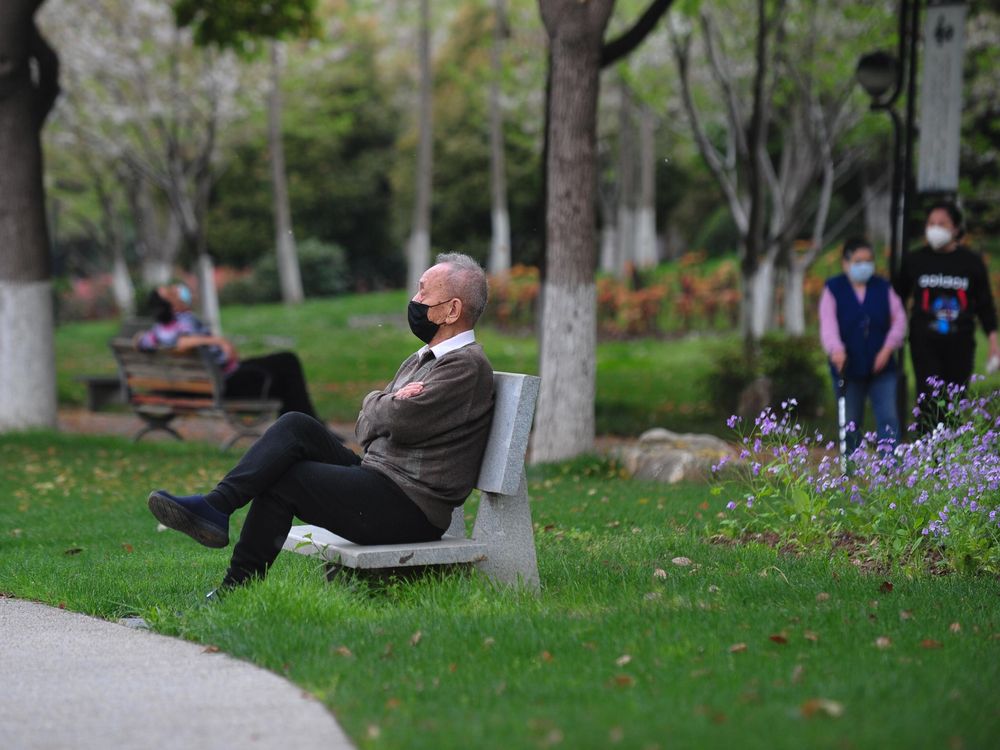 Elderly man rest on a bench after parks reopen in Wuhan on Thursday