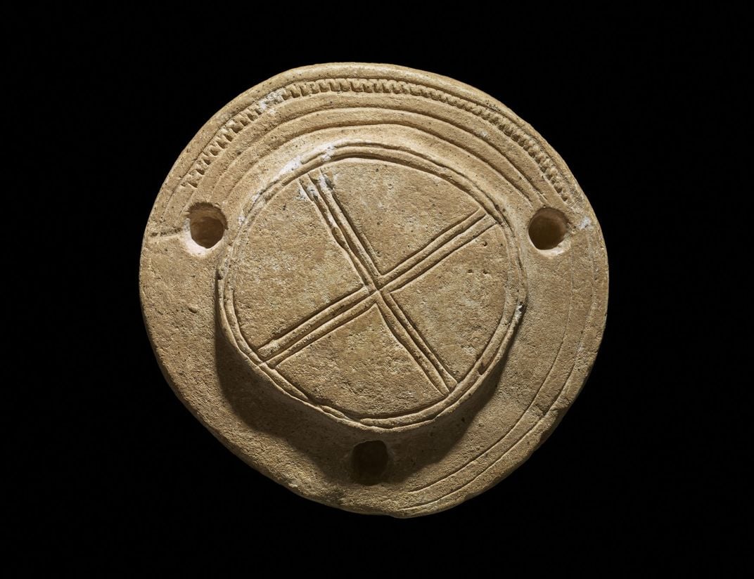 top view of stone drum with three holes and x symbol across the surface