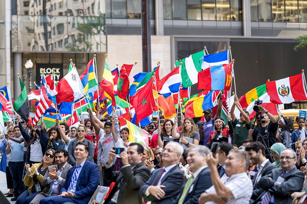 A crowd is standing with flags representing various countries.