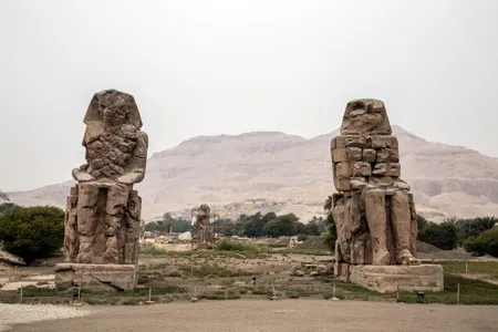 Statue of Memnon in the westbank in Luxor, with the community of Qurna in the background.