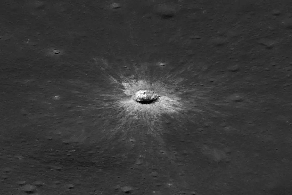 a white crater surrounded by grey landscape