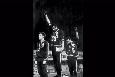 Smith (center) and Carlos (right) raised their arms and Norman wore a badge on his chest in support.