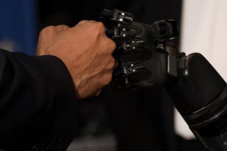 President Barack Obama fist bumps a robotic arm being controlled by electrodes implanted in Nathan Copeland's brain at the University of Pittsburgh on October 13, 2016.