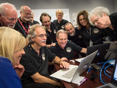 Members of the New Horizons team and journalists review new processed images from the New Horizons spacecraft, July 15, 2015. (Embedded journalist, standing left, Jeff Moore, science team, NASA Ames Research Center; Randy Gladstone science team Southwest Research Institute (SwRI); Andy Chaikin, science writer; Willam Lewis, science writer; Will Grundy, science team, Lowell Observatory; Maria Stothoff, media relations, Johns Hopkins University Applied Physics Laboratory (APL); Steve Maran, science writer. Seated; Laura Cantillo, NASA media relations, left, John Spencer, science team, Southwest Research Institute; and New Horizons Principal Investigator Alan Stern of SwRI.)