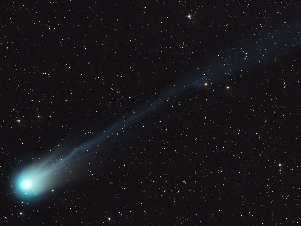 a comet streaks diagonally across the frame, with its bright green nucleus at the bottom left