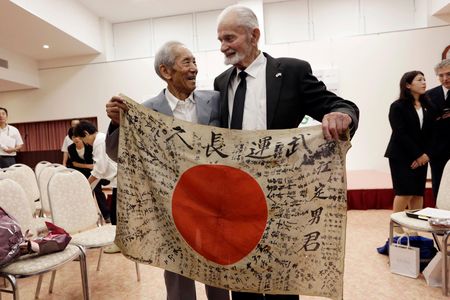 WWII veteran Marvin Strombo, right, and Tatsuya Yasue, an 89-year-old farmer, left, hold a Japanese flag with autographed messages that belonged to Yasue's brother Sadao Yasue, who was killed in the Pacific during World War II.