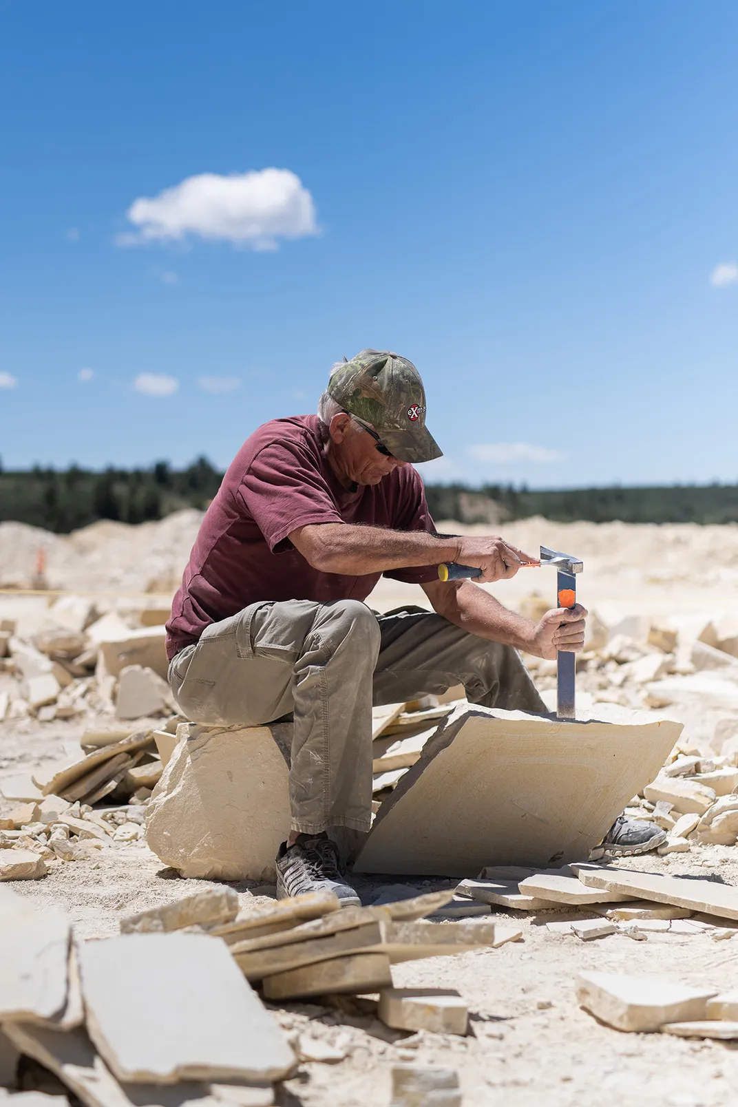 A tourist at American Fossil Quarry uses a hammer and chisel to split shale rock to look for fossils.