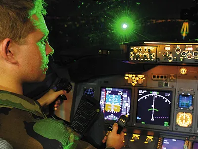 Air Force Second Lieutenant Paul LaTour is illuminated by a green laser during a landing in a Boeing 737 flight simulator at the FAA center in Oklahoma City. The Air Force and FAA worked to determine what level of laser exposure is safe for pilots.