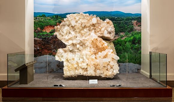 Museum display of the Berns Quartz from the front. The specimen is behind counter-height glass with a backdrop of Arkansas' Ouachita Mountains.