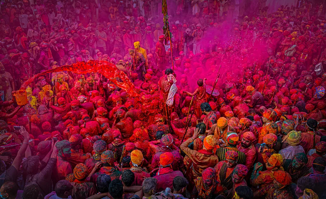 a large crowd covered in colorful powder during Holi Festival