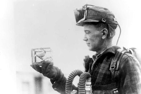 Mining foreman R. Thornburg shows a small cage with a canary used for testing carbon monoxide gas in 1928.