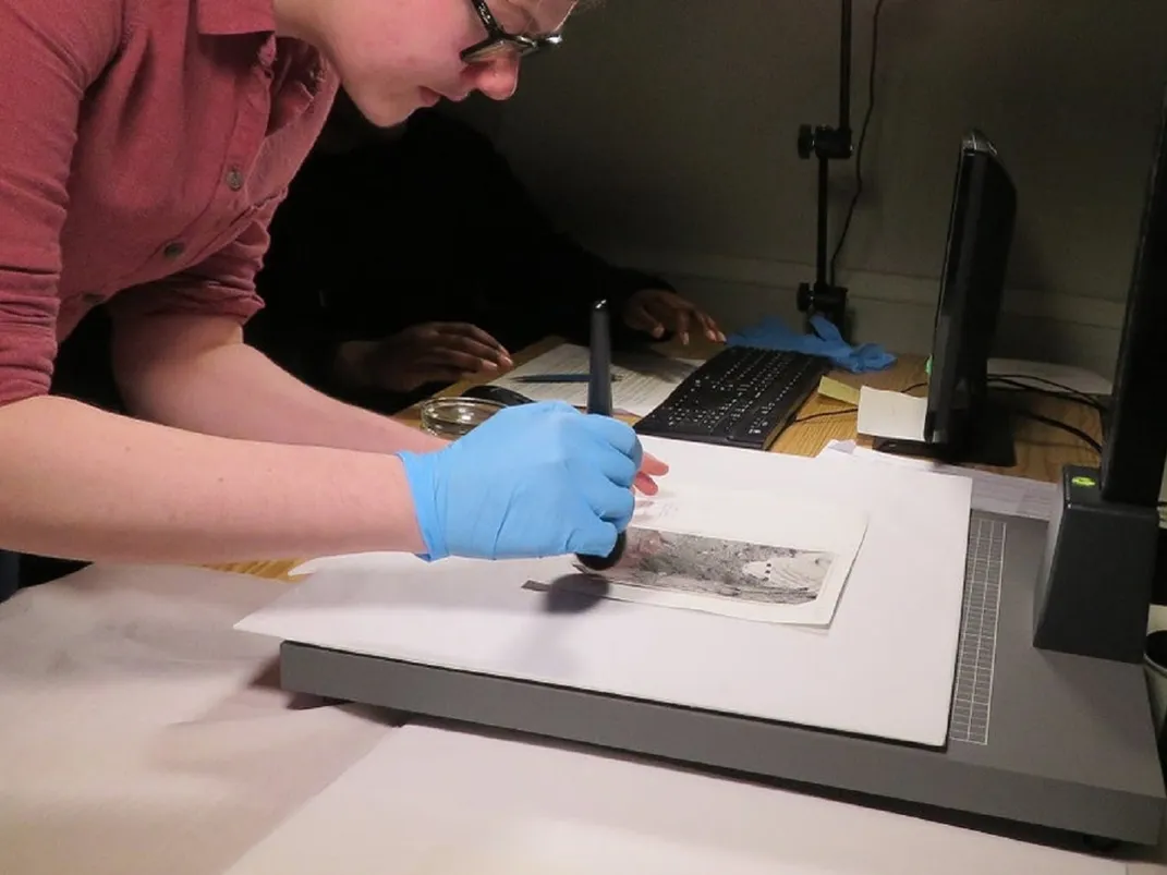 A worker digitizes one of the photographs