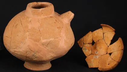 A reconstructed ceramic feeding bottle with a side spout displayed next to an enameled copper rooster figurine in a museum case.