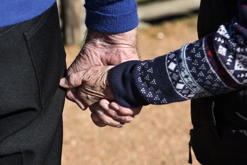 Close-up shot of two elderly hands holding each other
