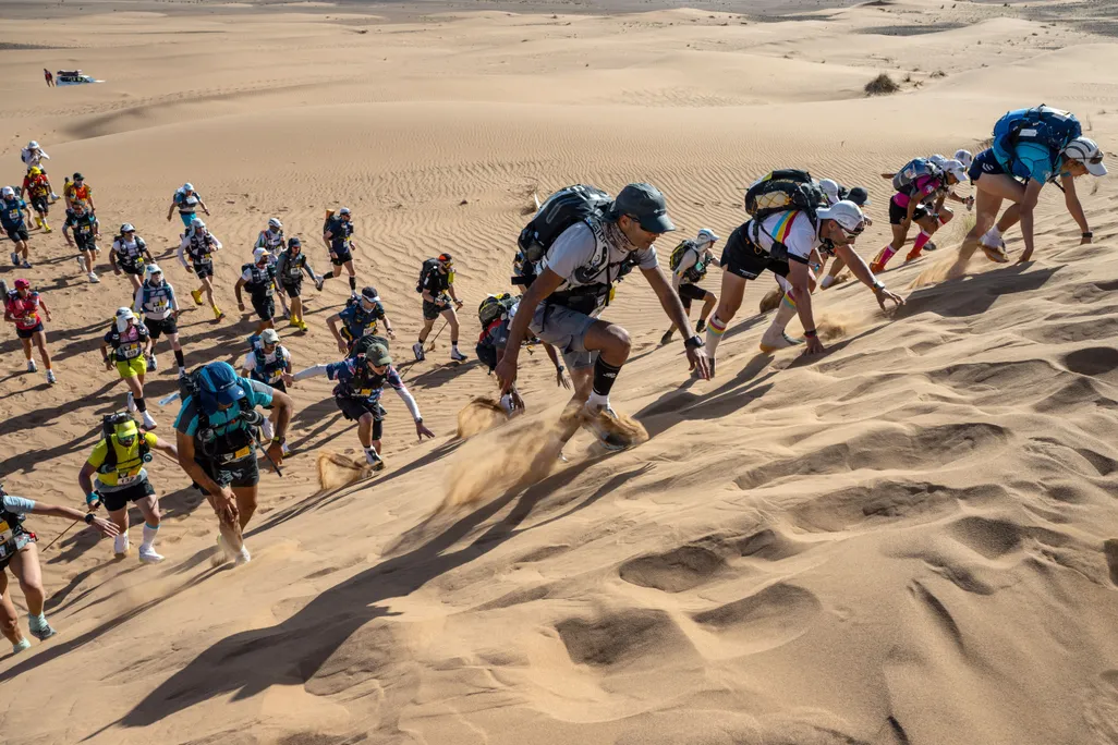 Runners climbing a sand dune