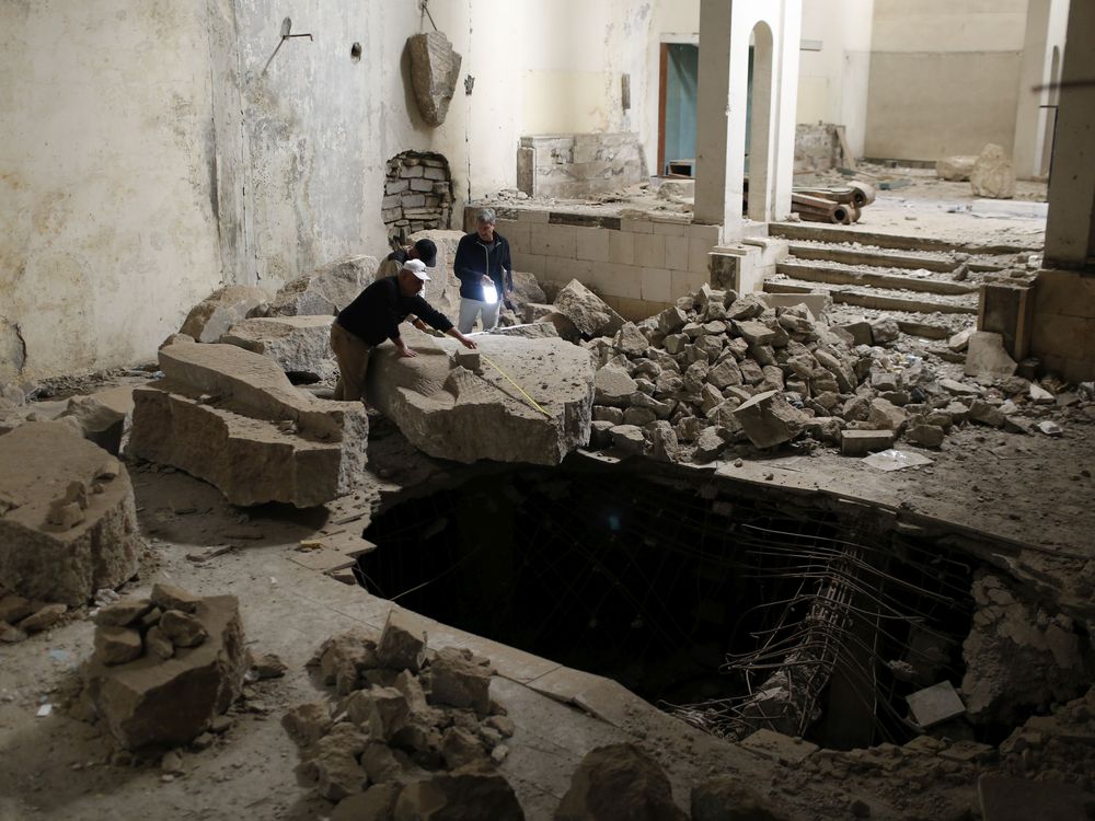 Three people look at ruins