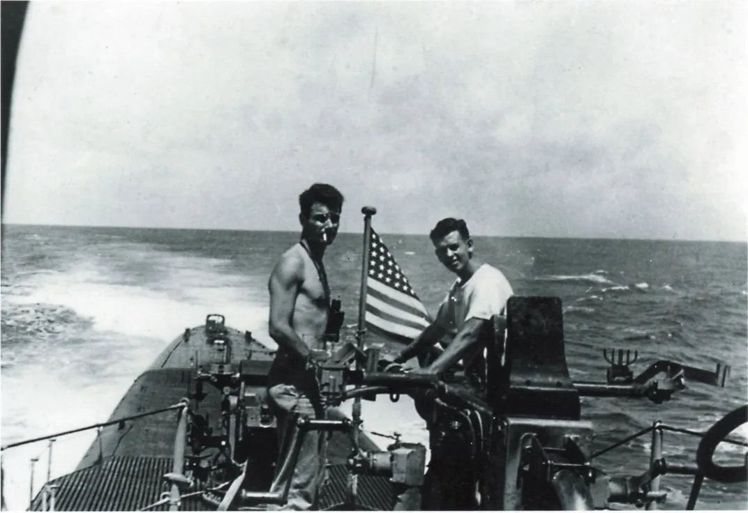 Black and white photo showing two men on a submarine