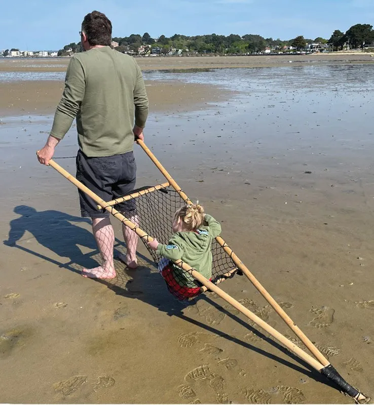 Person pulling a child in a wooden vehicle