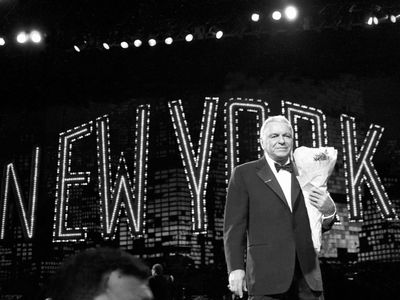Frank Sinatra clutches a bouquet of flowers handed to him by an admirer following his show at Radio City Music Hall in New York City, 1990
