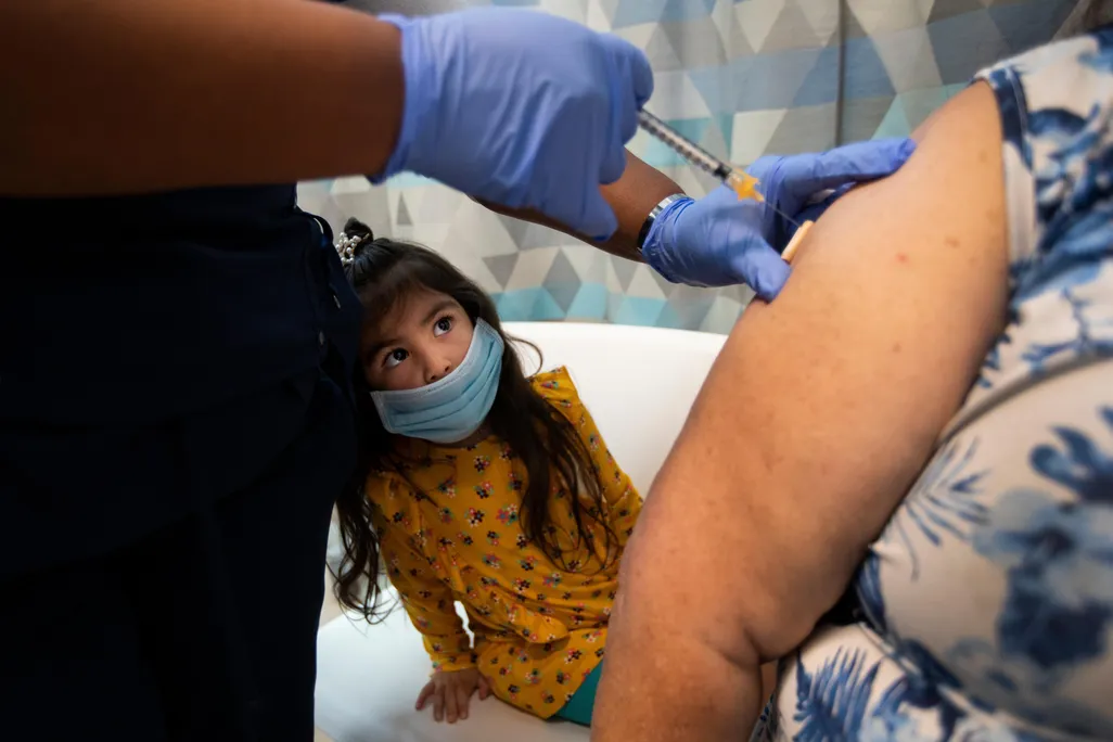 A young girl looks on as both of her grandparents are vaccinated at a clinic in Los Angeles