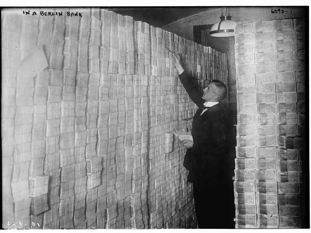A man standing next to stacks of German marks at a Berlin bank