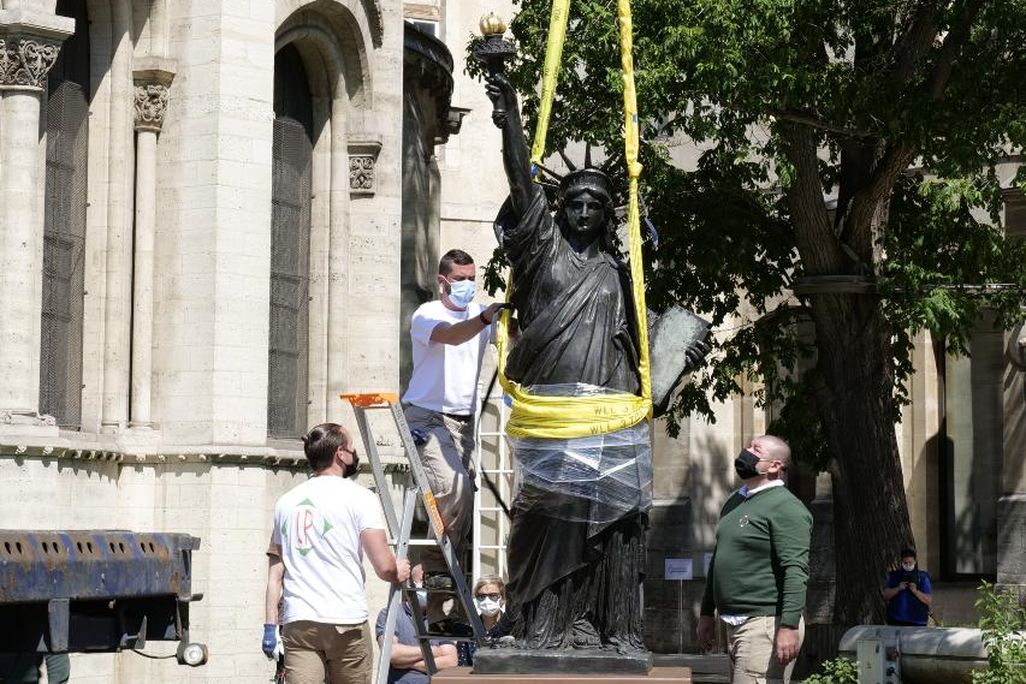 Workers remove a Statue of Liberty replica from its plinth