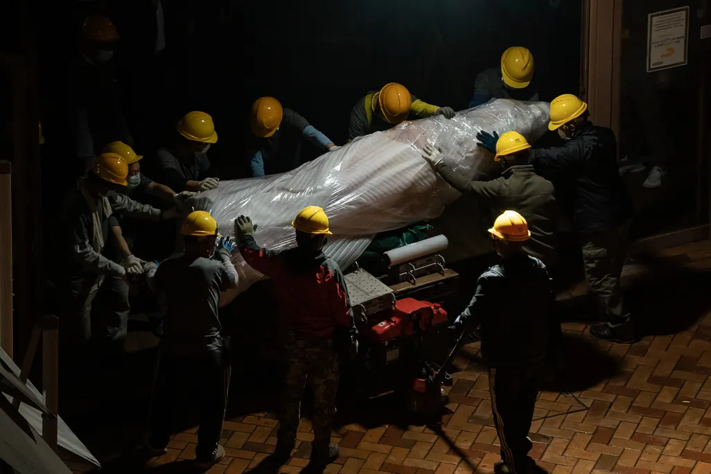 Workers remove part of the dismantled Pillar of Shame