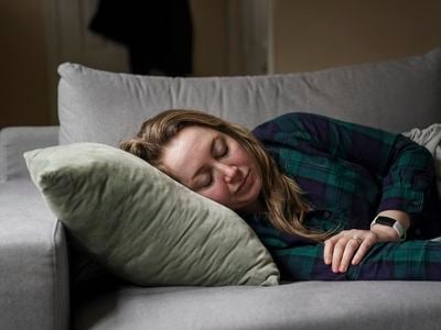 A woman with long Covid, suffering symptoms including extreme fatigue and brain fog, rests on her couch on February 3, 2022.