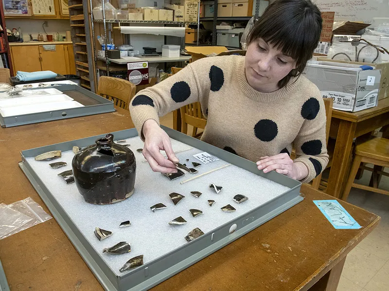 Archaeologist examines fragments of Chinese pottery