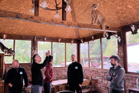 Dime Melovski gestures at lynx displayed in a hunter&rsquo;s lodge in North Macedonia. The hunters found the lynx dead on the road and asked the scientists for permission to taxidermy it.