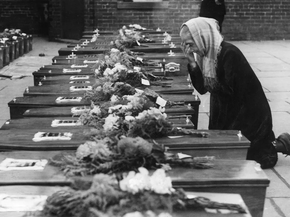 A woman kneels in prayer in front of children's coffins in Freckleton, England.