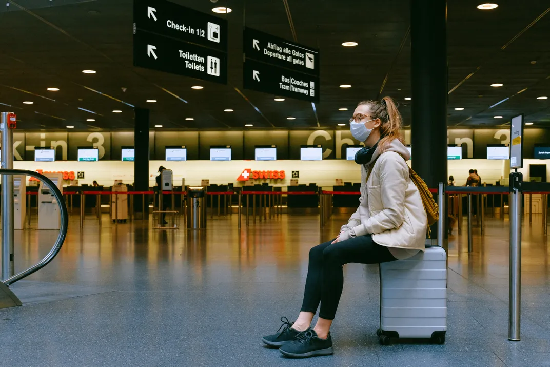 Woman sitting in airport wearing a mask