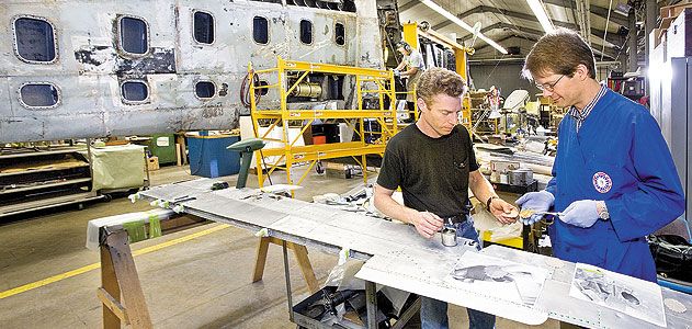 Whenever possible, original materials are saved. Project lead David Wilson (left) and chief conservator Malcolm Collum examine original fabric patches, used to cover bolt holes in the wing.